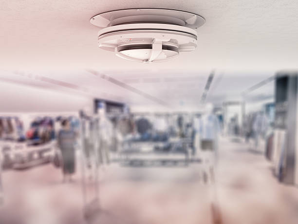 A commercial fire alarm sits on the ceiling of an office.