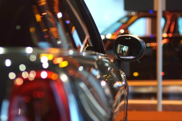 A new car sits underneath a parking lot light.